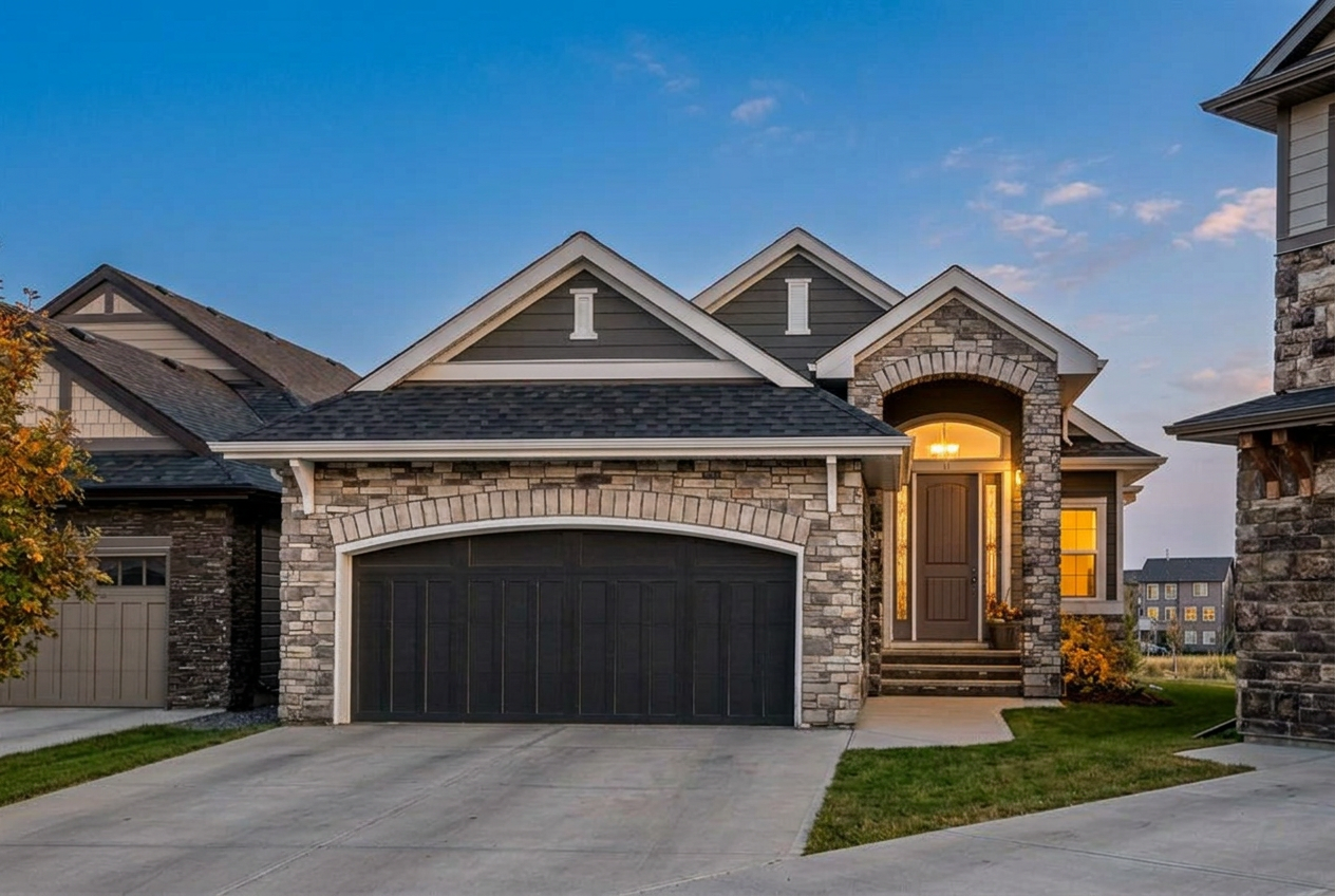 Stone-front walk-out bungalow at 44 Legacy Cove SE at dusk, shown with an AI-adjusted early-fall season